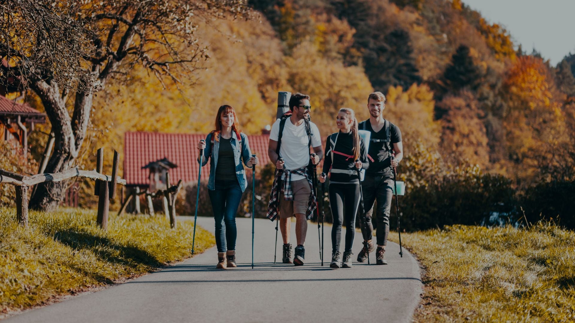 Four people hiking on a path with autumn foliage in the background